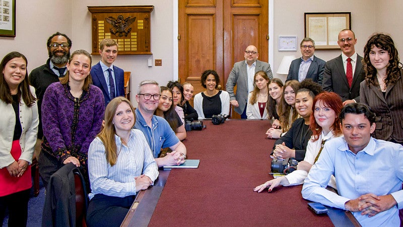 University of Oregon School of Journalism and Communication students look at the camera while sitting around a large conference table