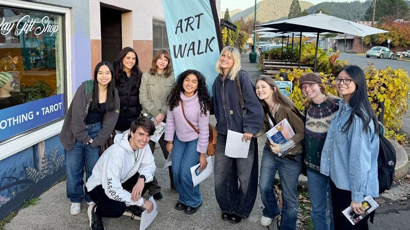 a group of students pose in front of a banner promoting the Oakridge Art Walk