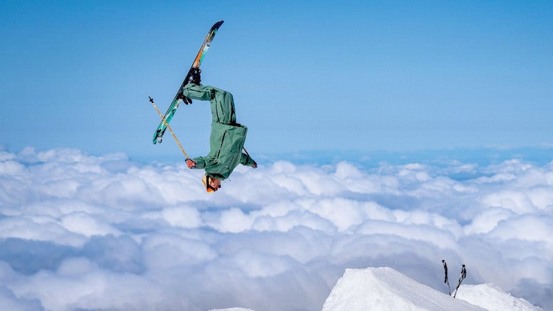 a skier appears to float over clouds while doing a backflip 