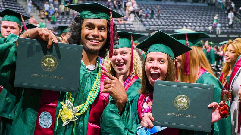 University of Oregon students from the School of Journalism and Communication hold up their diplomas at the graduation ceremony