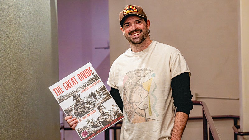 Kyle LaMontagne holding a poster for his documentary "The Great Divide"