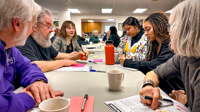 students and community members sit around a conference table