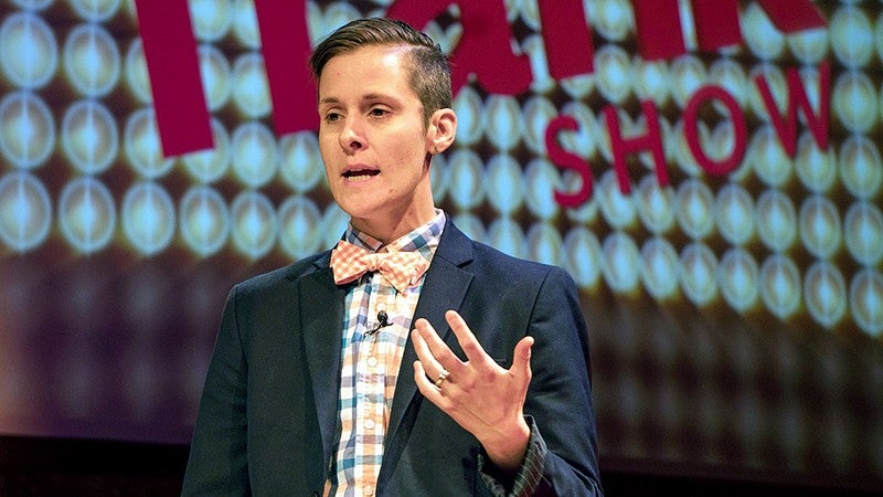 Dr. Erica Ciszek speaks in front of a screen while wearing a brown blazer.