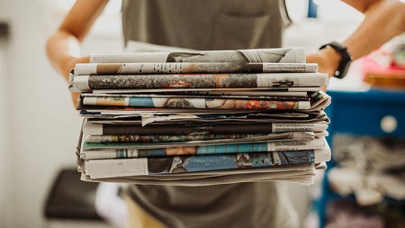 arms holding stack of newspapers