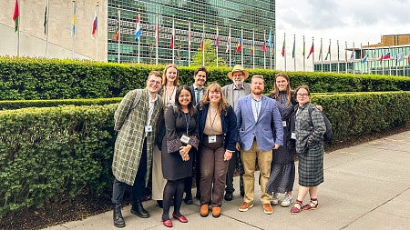 a group of SOJC students and faculty pose outside the UN building in New York