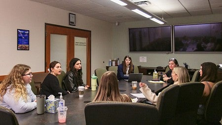 students have a discussion while sitting at a conference table