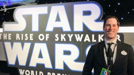 Alex Horwitch posing in front of a sign that says "Star Wars The Rise of Skywalker World Premiere"