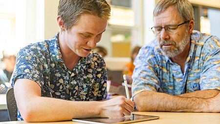 science communication minor student October Graham sketches on an iPad as professor Torsten Kjellstrand watches