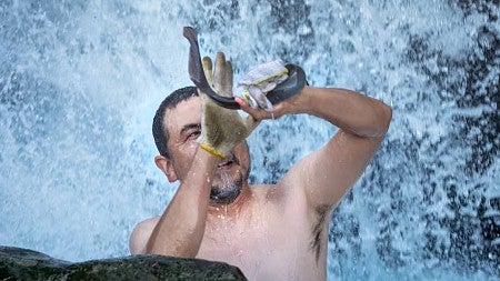 a person catches a lamprey while standing amid splashing water