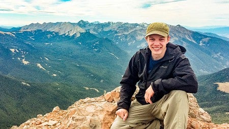 Travis Wilson poses on top of a mountain in Montana