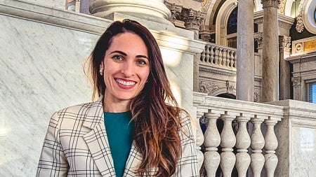 Priya Sage poses in front of grand marble columns and balustrades and an ornate ceiling