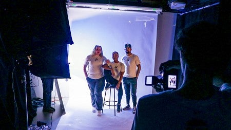 three students pose for a photo in the SOJC photo studio