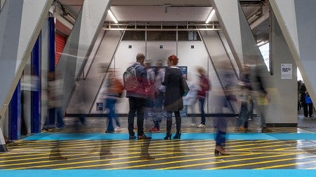 two people stand still in the middle of a modern atrium, with blurry images of other people surround them