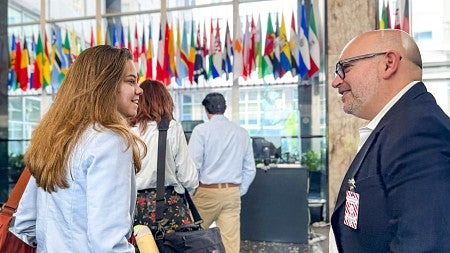 A young woman turns to look at Jason Rezaian in the lobby of a building with dozens of flags in front of a wall of windows