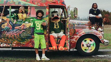 members of the University of Oregon football team and the UO Duck mascot pose with the iconic Furthur bus once owned by Ken Kesey