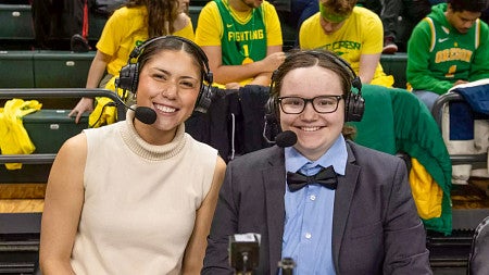 two female student broadcasters pose at an Oregon basketball game