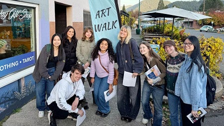 a group of students pose in front of a banner promoting the Oakridge Art Walk