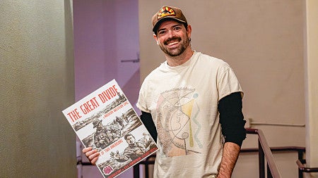 Kyle LaMontagne holding a poster for his documentary "The Great Divide"