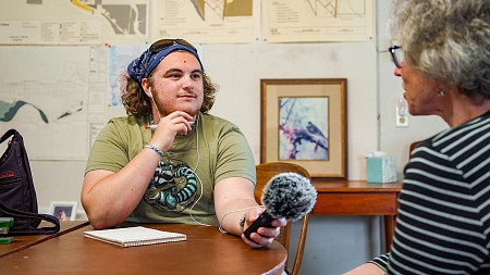 SOJC journalism student Kai Schrosk records an interview with an Oakridge resident