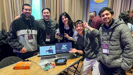 a group of people pose with laptops at MIT's Reality Hack hackathon