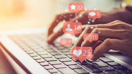 stock image of hands typing on a laptop with superimposed social media notification icons