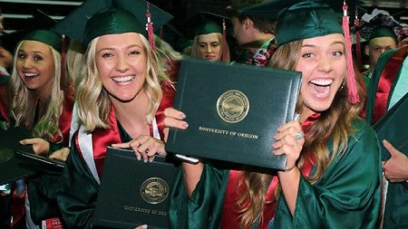 Three female students with their diplomas at commencement