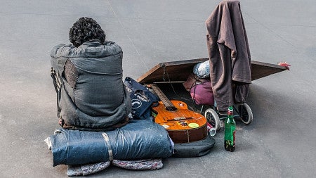 Homeless person sitting next to items.