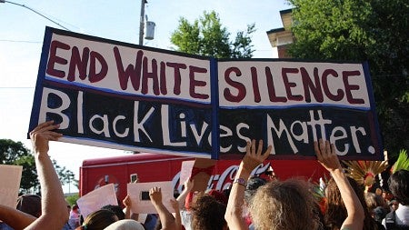 Protestors holding sign saying "End White Silence, Black Lives Matter"