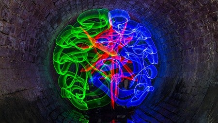 Bright swirls of green, red and blue come together to form the image of a human brain. 