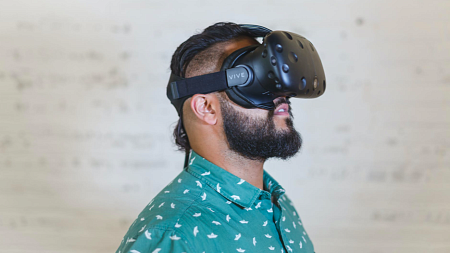 A person wearing a teal collared shirt using a VR headset.