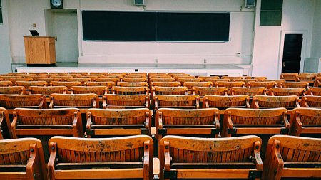 An empty college lecture classroom with a blackboard at the front of the room.