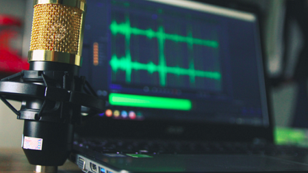 A gold condenser microphone near a laptop computer (By Seej Nguyen from Pexels).