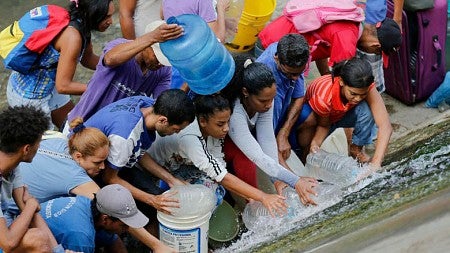 People in Venezuela are forced to fill up buckets of river water due to disabled electric water pumps. 