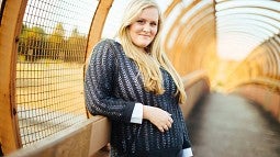 Kiva Hanson stands on bridge wearing a gray sweater. 