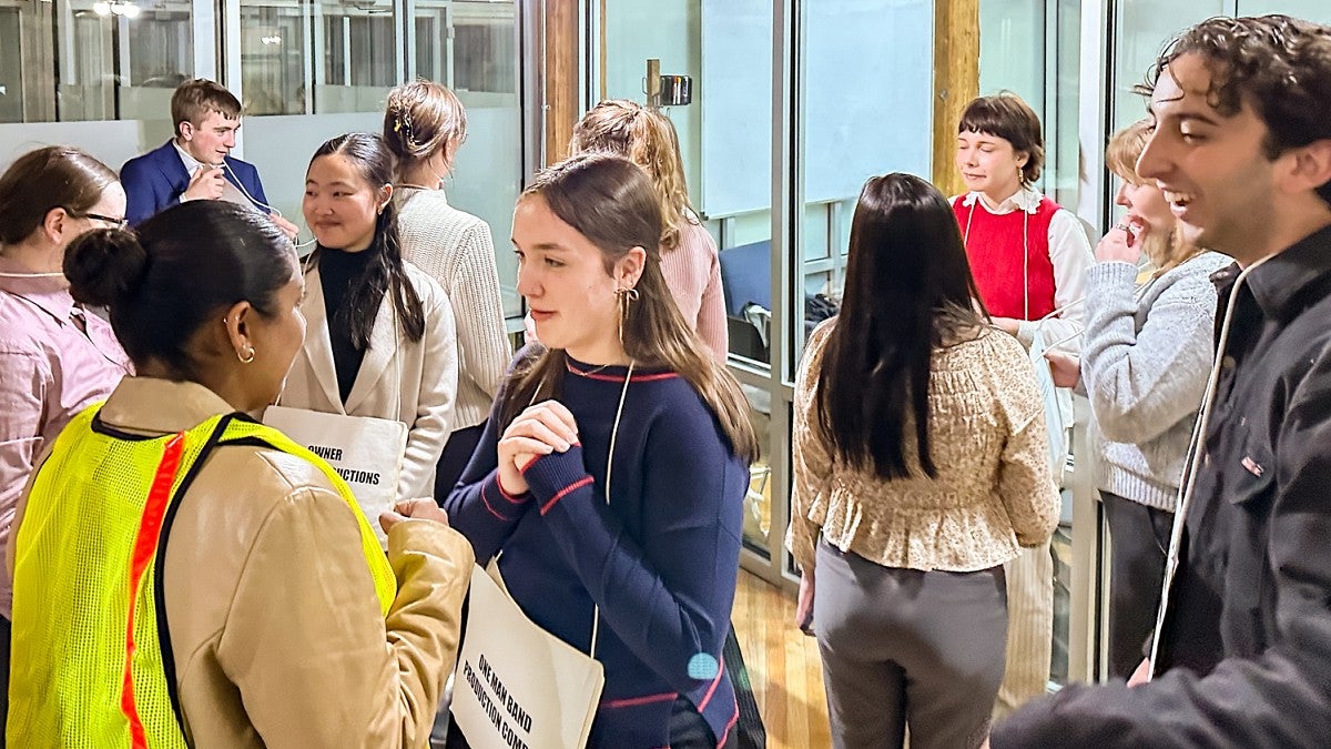 a group of students wearing signs around their necks talk to each other