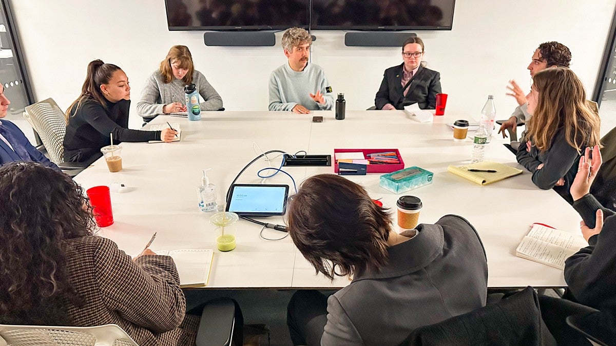 a group of people having a discussion while sitting around a conference room table