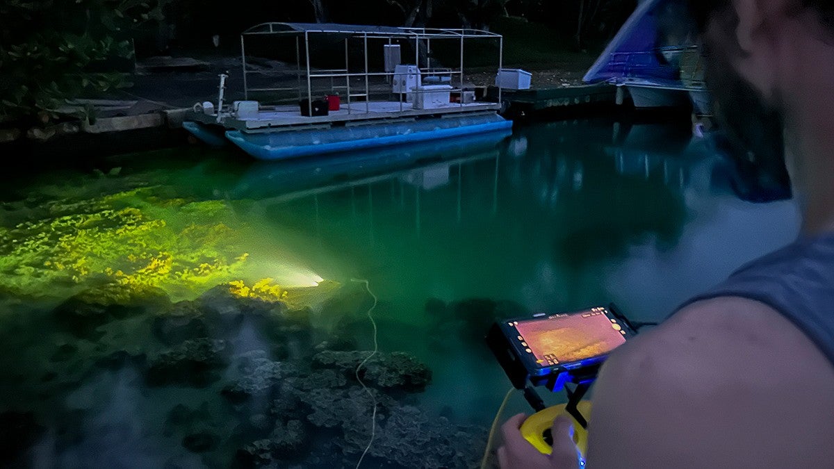 Sam Morrison uses photogrammetry equipment at night in the water