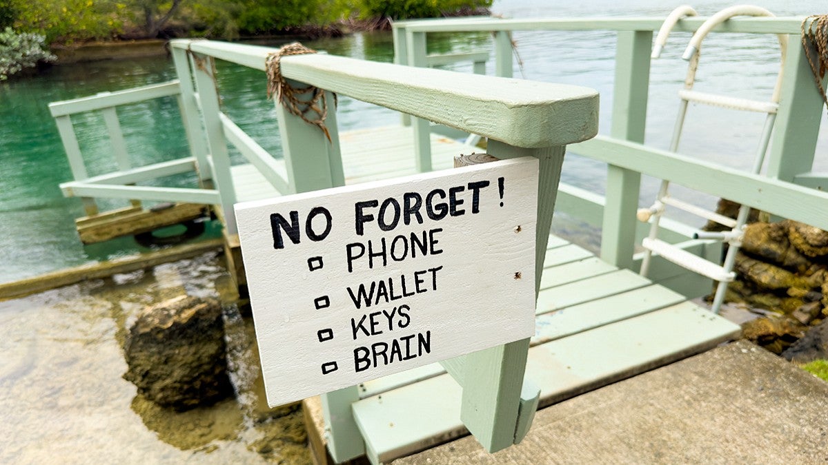 a handpainted sign on a dock that reads "No Forget! Phone; Wallet; Keys; Brain"