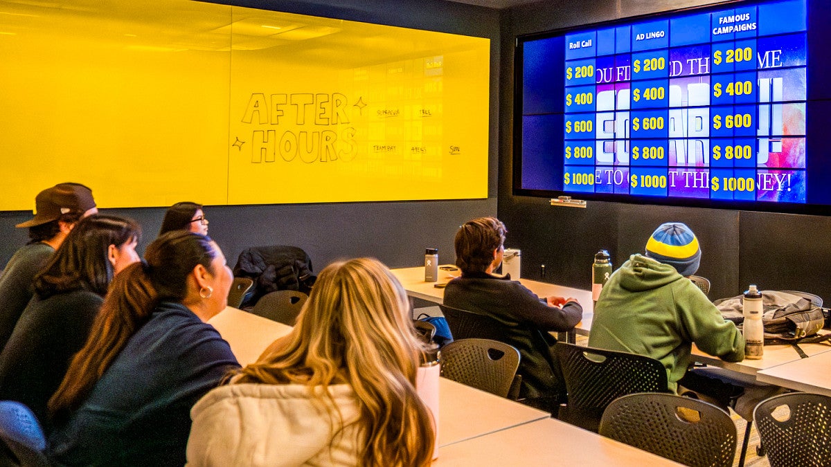 students in the After Hours advertising club at the UO School of Journalism and Communication face a large digital screen designed to look like Jeopardy