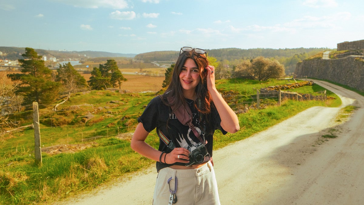 Josie Brown poses holding a camera on a road in the countryside of Denmark
