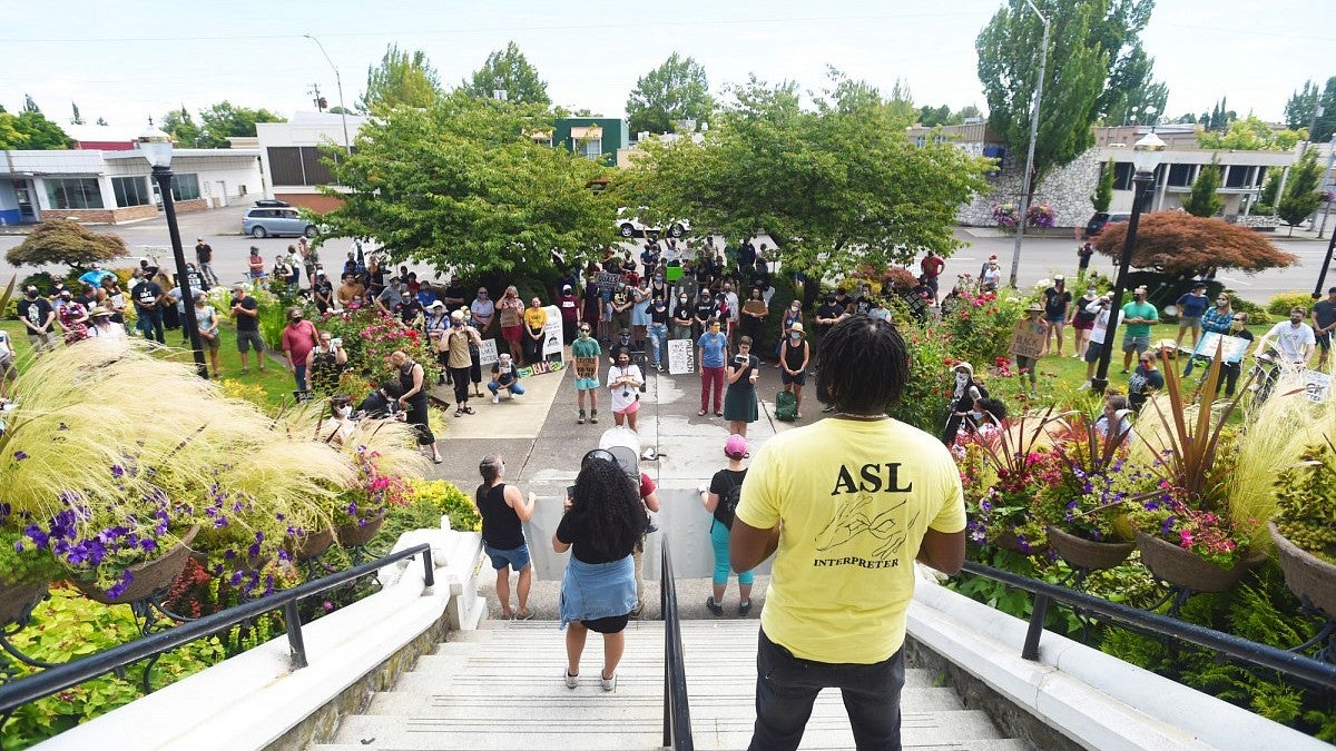 A group of people stand together at a Black Lives Matter rally to protest police brutality.