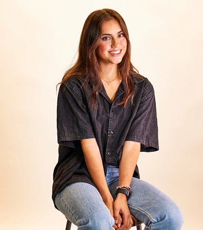 Chloe Montague sits on a stool wearing a black oversized shirt