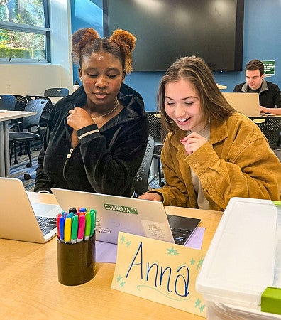 two students look at a laptop