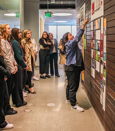 students watch a person point at images on a wall