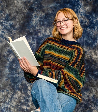 Grace Newlin poses for a portrait holding a book