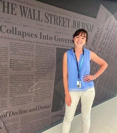 Sierra McClain poses in front of a wall with images of the Wall Street Journal