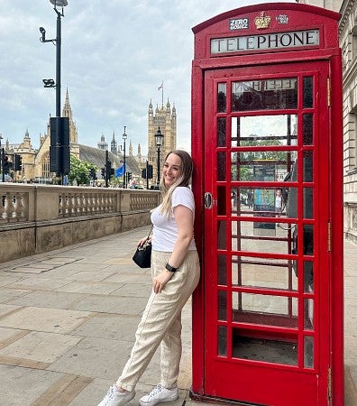 Kaitlyn Bullentini leans against a red telephone booth in London