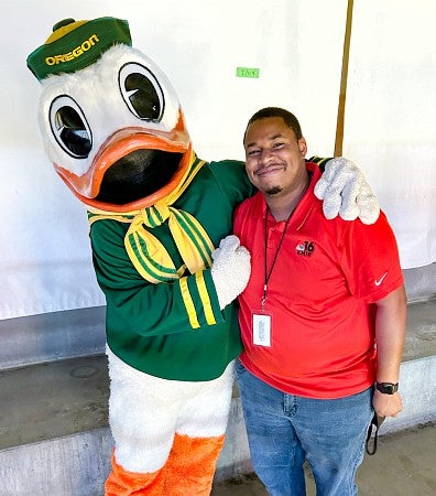 Ronald Clark poses with the Oregon Duck mascot while on assignment for his TV news job as a sports reporter