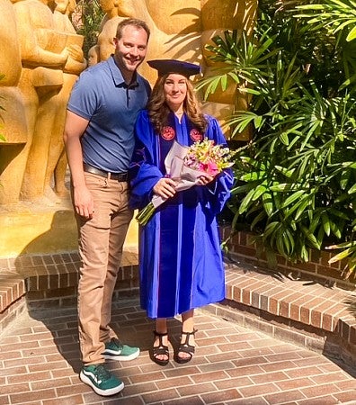 Renee Mitson wearing doctoral robes poses with another person