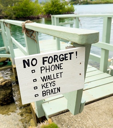 a handpainted sign on a dock that reads "No Forget! Phone; Wallet; Keys; Brain"